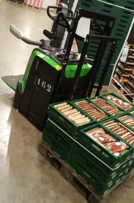 An electric pallet truck loaded with green crates in a warehouse in the Netherlands